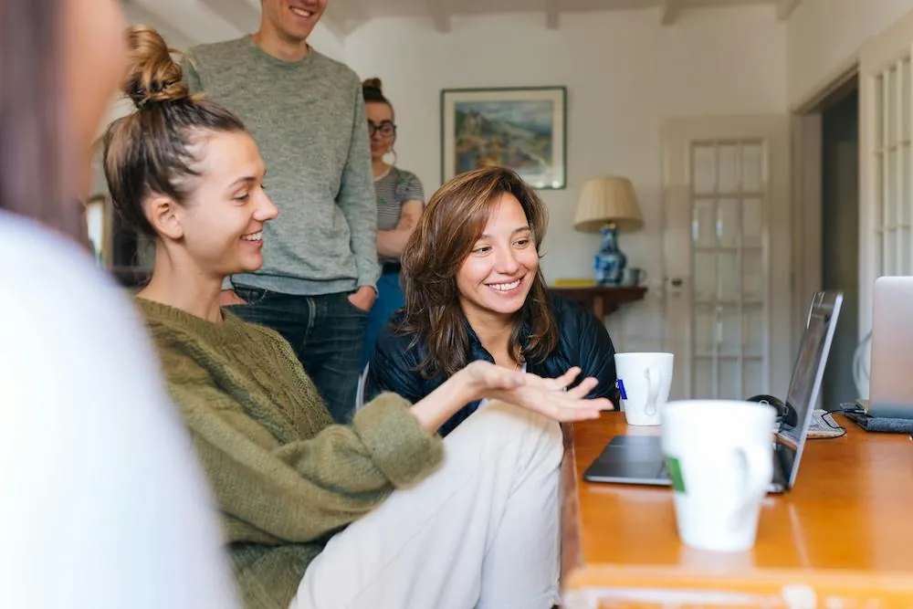 group of young people in living room at laptop