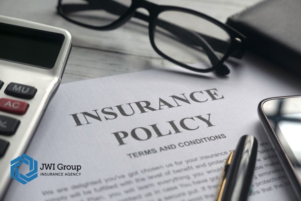 Insurance policy document with glasses, calculator, and pen on desk