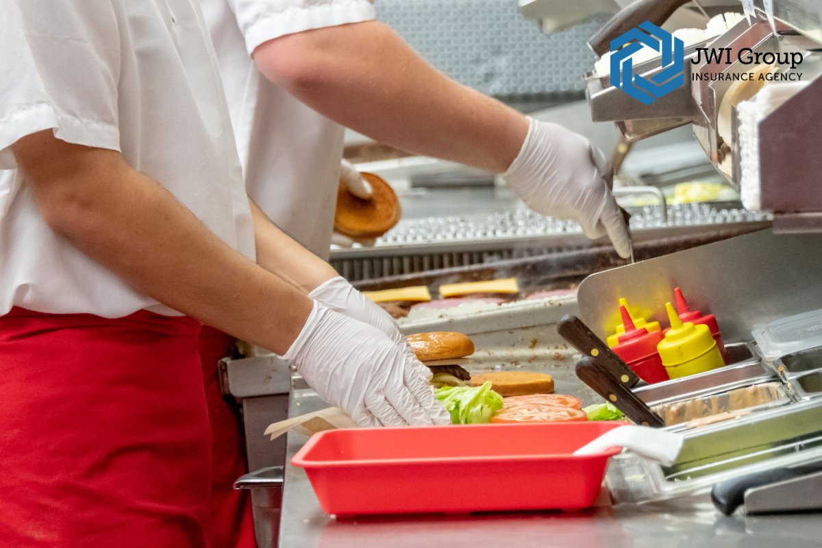 Restaurant staff preparing food in a commercial kitchen with gloves and safety protocols, demonstrating workplace safety practices.
